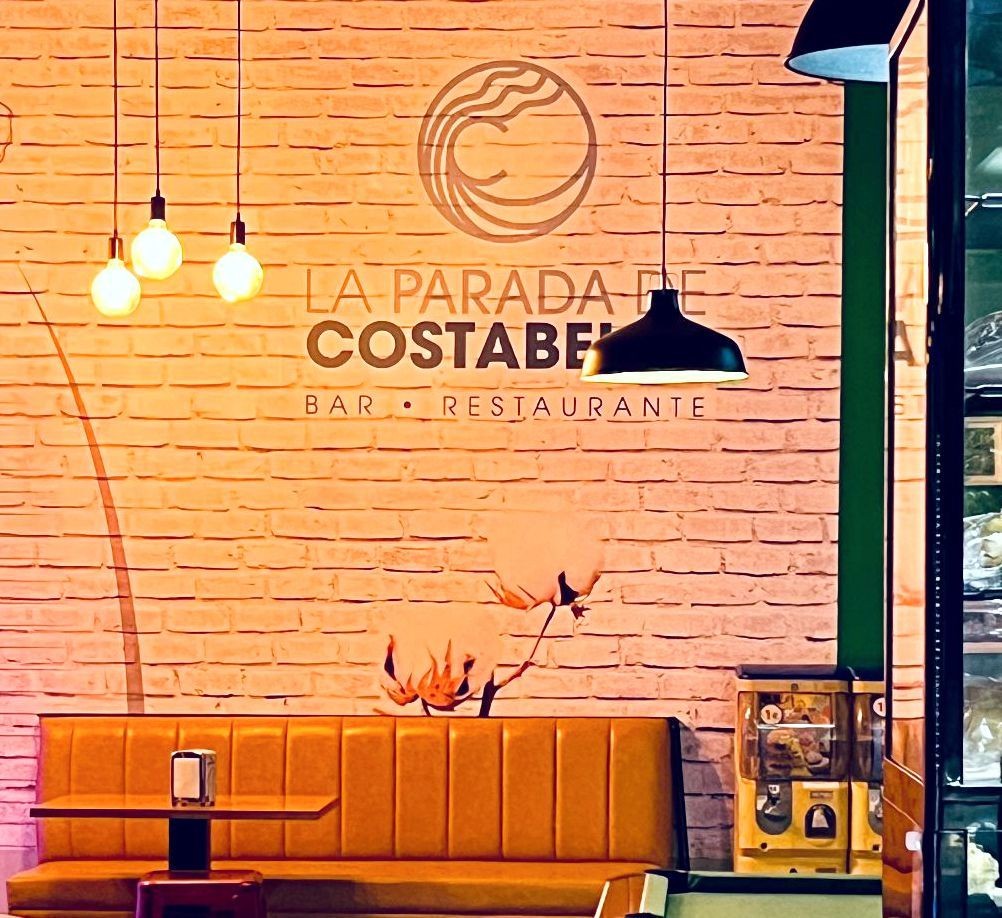 Cozy restaurant interior with pendant lights, brick wall, and orange seating.